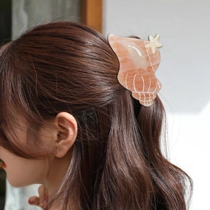 Pink conch acetate hair claw with white starfish on model's dark brown hair