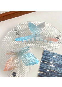 Macro detail of gradient acetate fish tail and butterfly hair claws with pearlescent finish