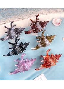 Détail de pinces à cheveux en forme de conque sur un fond de plage avec du sable