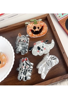 Vue détaillée de pinces à cheveux d'Halloween avec motifs citrouille et fantôme sur un plateau