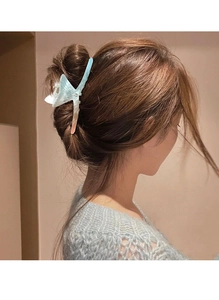 Detail view of the gradient blue acetate fish tail hair claw clip worn by a model