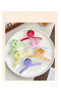 Lot de pinces à cheveux fruits colorés avec fraise et avocat sur une assiette en céramique
