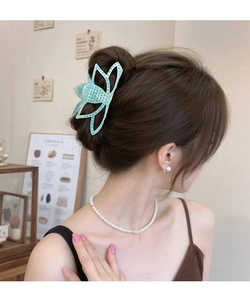 Détail d'une pince à cheveux papillon bleu clair avec strass portée par un mannequin