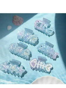 Detail of marine series hair claws featuring starfish and seashell designs with water ripple shadows