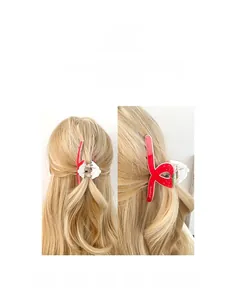 Détail d'une pince à cheveux fraise rouge avec feuilles vertes sur cheveux blonds