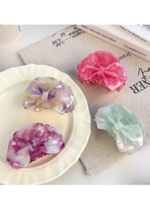 Detail of four colorful acetate bow hair claws in peach, purple, and green patterns