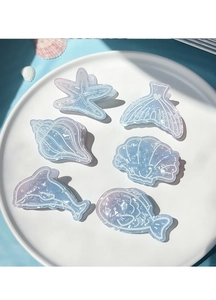 Detail view of various ocean-themed hair clips with blue glitter and marine elements