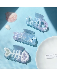 Detail of ocean-themed hair clips with iridescent dolphin and fishbone designs in soft blue