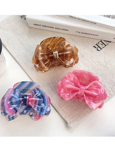 Detailed shot of bow-shaped hair claws in amber, pink marble, and colorful textures