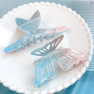 Gradient acetate fish tail and butterfly hair clips in blue and pink on a white plate