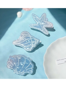 Detail of blue starfish, seashell and scallop hair claws in a summer beach scene
