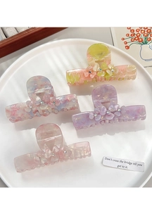 Detail of acetate hair claws with marble texture and rhinestone flowers in pastel colors