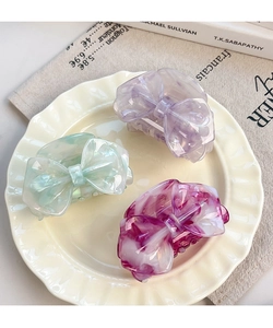 Three acetate bow hair clips with marble texture placed on a vintage ceramic plate