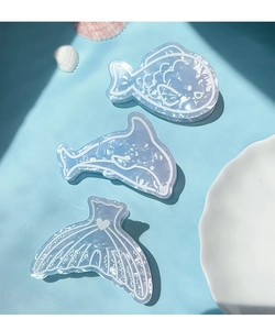 Detail of ocean-themed shark hair clips featuring pearlescent blue dolphin and fish tail designs
