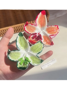 Détail de pinces à cheveux lys rouge et vert avec texture brillante et design floral