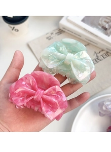 Close-up of pink and green marbled bow hair claws with elegant acetate texture