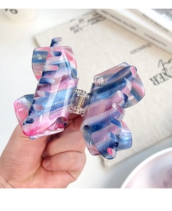 Detail of butterfly hair claw clip with pink and blue gradient marble texture and gold spring