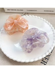 Detail view of pink and purple bow hair claws with marble texture in a decorative tray