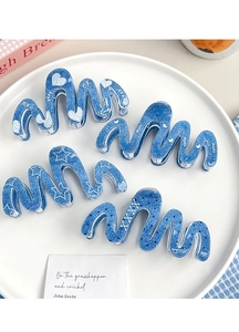 Detail von vier blauen Haarklammern in Denim-Optik mit weißem Aufdruck auf Tablett