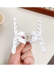 Détail d'une pince à cheveux papillon blanc translucide avec mécanisme à ressort métal