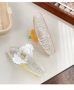 Gros plan de pinces à cheveux translucides avec des motifs d'orange et d'ananas