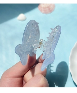 Close-up of translucent light blue butterfly hair claw clip with silver metal spring