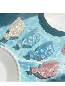 Detail of whale-shaped acetate hair claws with sparkling rhinestones and marble texture