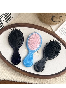 Three portable marble pattern mini hairbrushes in a decorative tray for hair massage