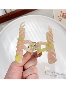 Close-up of pink and green marbled acetate hair claw clip with golden metal spring