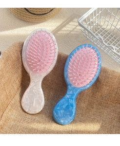 Detail view of mini acetate massage hair brushes in blue and white marble textures