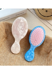 Detail of the pearlescent pink and blue acetate hair comb on a cozy textile background