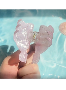 Detail of pink marble hair claw clip with golden spring over blue water background