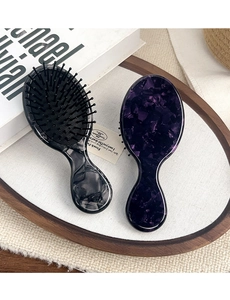 Close-up of marble acetate hair brushes with massage air cushions on a tray