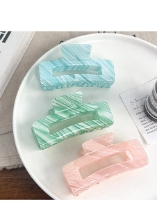 Three rectangular hair claws in pastel blue, green and pink with marble textures on a tray