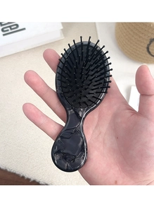 Close-up of portable acetate hairbrush with black marble texture and air cushion pins