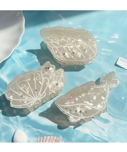 Close-up of ocean-themed acetate hair clips with shell and whale motifs and rhinestones