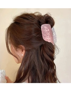 Detail of pink butterfly wing hair claw clip with white vein patterns on wavy brown hair