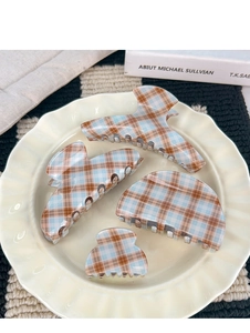 Set de quatre pinces à cheveux à carreaux marron et bleu sur une assiette en céramique