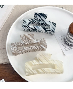 Detail view of large French candy colored PVC hair claws with stripes on a white plate
