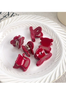 Close-up of red acetate floral hair claw with France Handmade text on ceramic tray