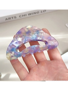 Detailed close-up of marble pattern acetate hair claw clip held for size reference