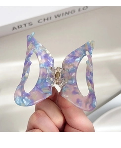 Detail of butterfly hair claw with oil painting marble texture and gold metal spring
