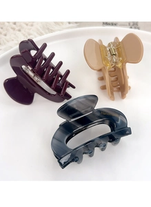 Gros plan de pinces à cheveux élégantes en acétate violet, beige et bleu marbré doré