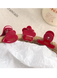 Close-up of red acetate hair clips set including heart and flower shapes in a basket