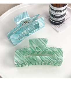 Detail of light blue and green striped PVC hair claw clips on a white tray set