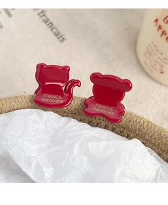 Macro view of small red acetate cat and bear hair claws with gold France Handmade text