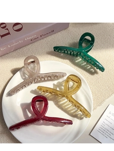 Detail shot of four elegant large hair claws in various colors on a ceramic tray