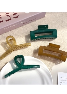 Assorted jelly color hair claws in amber and green displayed on a soft knit surface