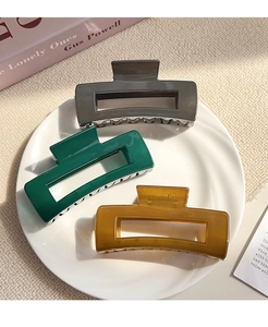 Close-up of three rectangle hollow hair claws in gray green and amber colors