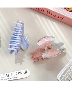 Close-up of luxury acetate hair claws with marble texture and sparkling rhinestone details
